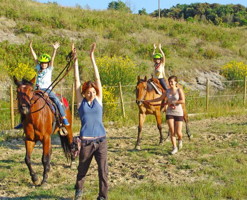 2 Kinder mit Reitlehrerinnen während einer Reitstunde auf Ponys